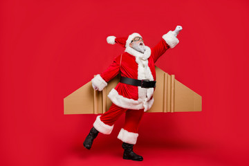 Full size photo of amazed elderly superhero christmas father impressed by fly up turbo speed of his magic imagine rocket wings scream omg wear cap hat isolated over red background