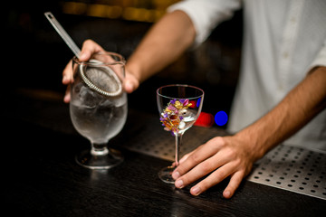 Bartender pouring alcohol from glass with a strainer