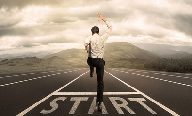 Businessman jumping on a starting grid with the meadow on the background. Caucasian man, empoyer in...