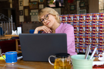 A woman sitting at a table with a Cup of tea and a laptop working in a cafe.
