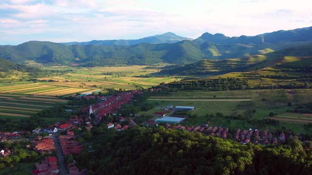 A wide angled fly over drone shot of the village of Coltesti and the Coltesti mountain range, in Romania. The valleys and gorges expand far into the distance.