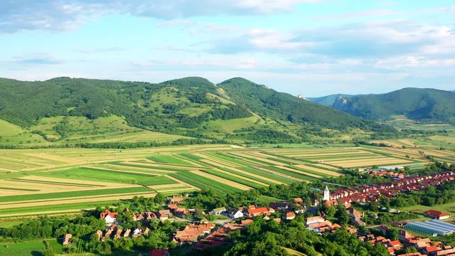 A wide angled fly over drone shot over the village of Coltesti and the Coltesti mountain range, in Romania. The valleys and gorges expand far into the distance, the village fills the foreground.