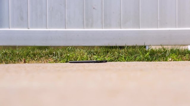 Broken touchscreen tablet falling across the concrete in slow motion