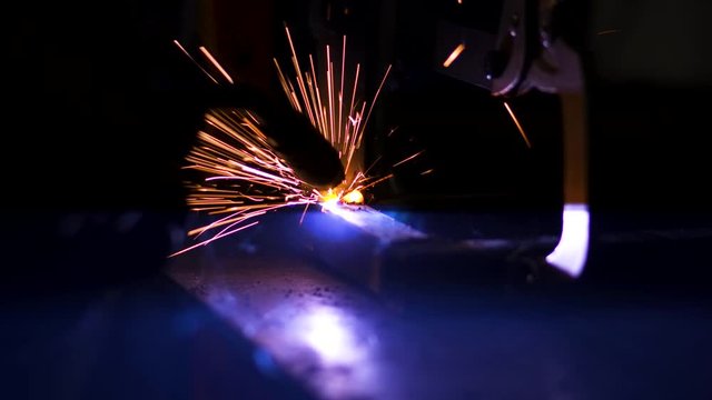 MIG metal inert gas welding metal together with clamp and sparks flying close up