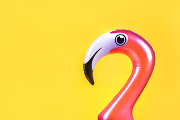 Summer fun concept with pink inflatable flamingo head on a yellow background with copy space © Dmytro