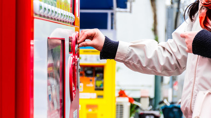 A japenese girl buying a drink from a vending machine in Osaka.