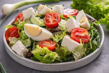 Diet salad with fresh greens, eggs, tomatoes and cheese. Closeup