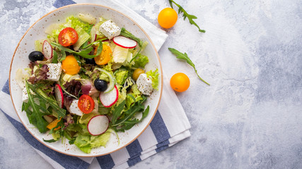Diet salad with fresh vegetables, lettuce, arugula and cheese. Top view. Copy space