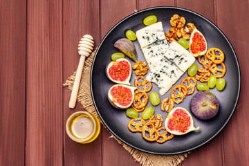 Cheese plate with blue cheese, honey, walnuts, figs, grapes, pretzels