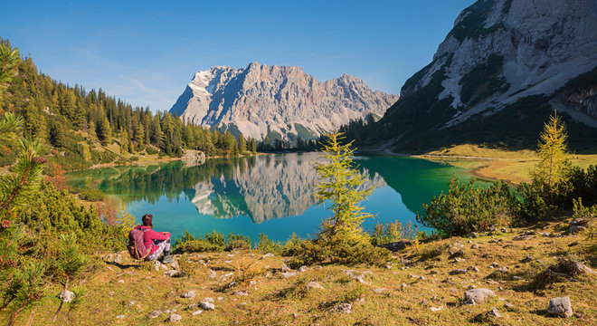 Junge Frau mit Rucksack bewundert das Zugspitz Panorama mit der Spiegelung im Seebensee
