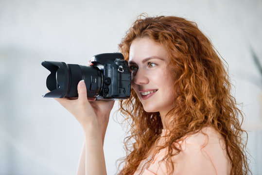 Happy woman using photo camera in modern light interior