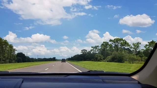 View out of windshield while driving on road during day time, Kissimmee Florida.