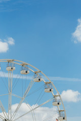 Ferris wheel on the blue cloudy sky. Background concept of happy holidays time.
