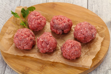 Raw meatball over wooden background