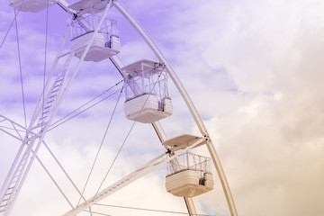 Ferris wheel on the colorful cloudy sky. Background concept of happy holidays time.
