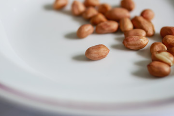 Raw peanuts on white dish