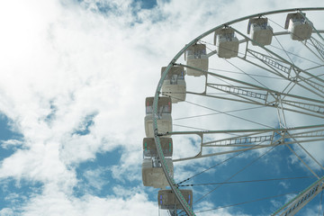 Ferris wheel on the blue cloudy sky. Background concept of happy holidays time.