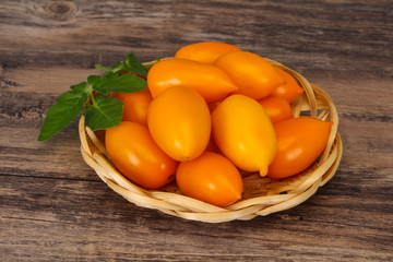 Yellow tomato heap in the wooden bowl