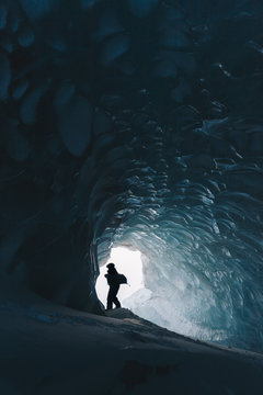 Silhouette of a person standing inside an ice cave on Svalbard