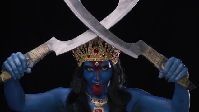Ancient goddess Kali is crossing two blades and showing her red tongue