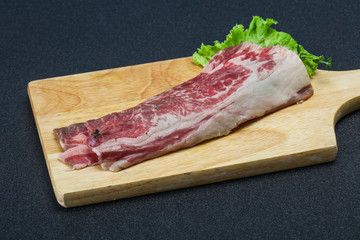 Raw beef bacon over wooden board