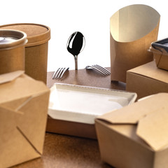 A metal spoon and two forks, disposable tableware made of paper on a cork table. isolated white background