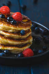 Pancakes with honey and berries on a wooden table