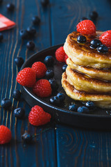 Pancakes with honey and berries on a wooden table
