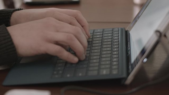 Female hands typing on a tablet or laptop keyboard with shallow focus