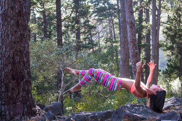 Beautiful athletic woman surrounded by trees in a forest levitating in mid air at sunrise.