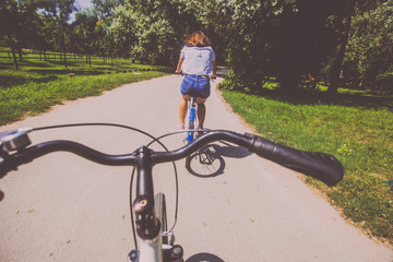 Pretty Young Woman Riding Bicycle In The Park Rear View