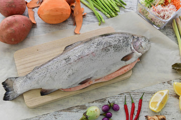 Raw fish for cooking with vegetables on the kitchen table.