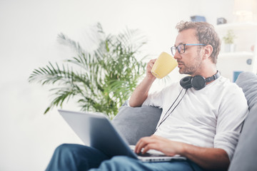 Man listening to music and using laptop in the living room.