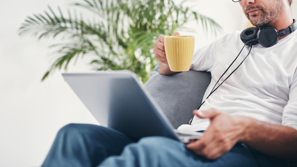 Man listening to music and using laptop in the living room.