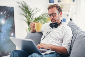 Man listening to music and using laptop in the living room.