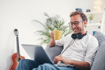 Man listening to music and using laptop in the living room.