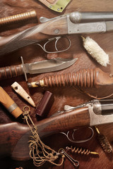 Hunting concept with shotgun, knife and ammunition for hunting arranged on brown background.