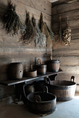 interior of old wooden cottage hallway with dried flowers, wooden pots, buckets and barrels lit by morning sun