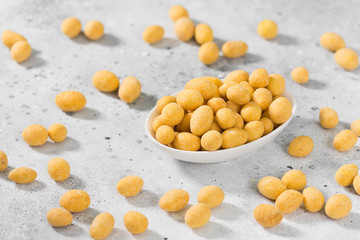 Peanuts in cheese sauce in a white bowl on a light gray table