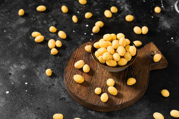 Fototapeta na wymiar Peanuts in cheese sauce in a dark bowl on a black table