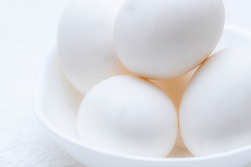 Close up shot of whole white eggs in a white bowl