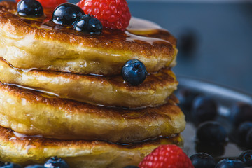 Pancakes with honey and berries on a wooden table