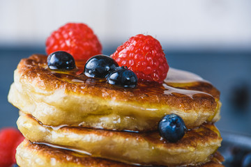 Pancakes with honey and berries on a wooden table