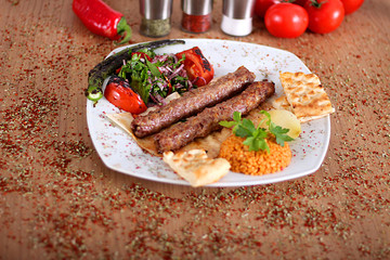 Roasted turkey kebabs with fresh vegetables on a wooden table filled with Turkish spices