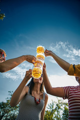 Group of young people enjoying and cheering beer outdoors.