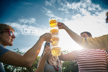 Group of young people enjoying and cheering beer outdoors.