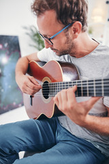 Man playing acoustic guitar in the living room.