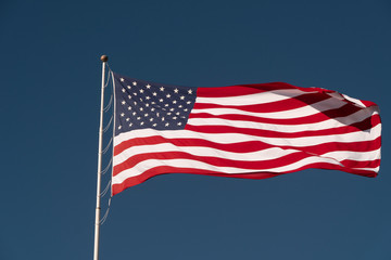 Flag of the USA is waving on blue sky background. National symbol of the United States of America, independence, patriotism, freedom, honor, democracy concept