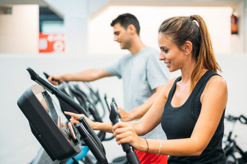 Naklejka na ściany i meble Adult couple is working out on Step climber machine in fitness gym for healthy lifestyle concept.