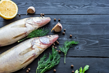 Two raw fish on a black wooden table, top view with copy space.